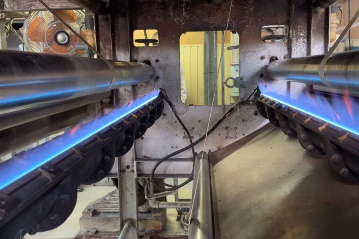 毛焼き機に生地を通し、ガスバーナーで表面の毛羽を取り除きます。